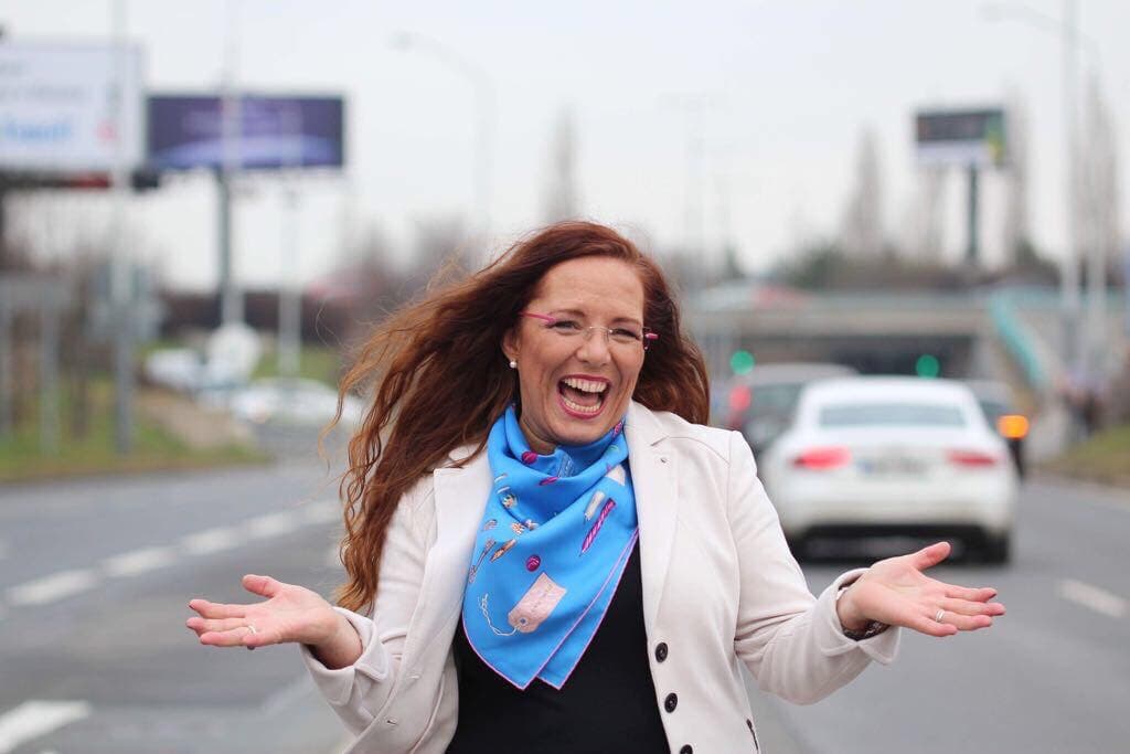 Vladislava Pospíšilová stojí s rozpřaženýma rukama uprostřed silnice a směje se
